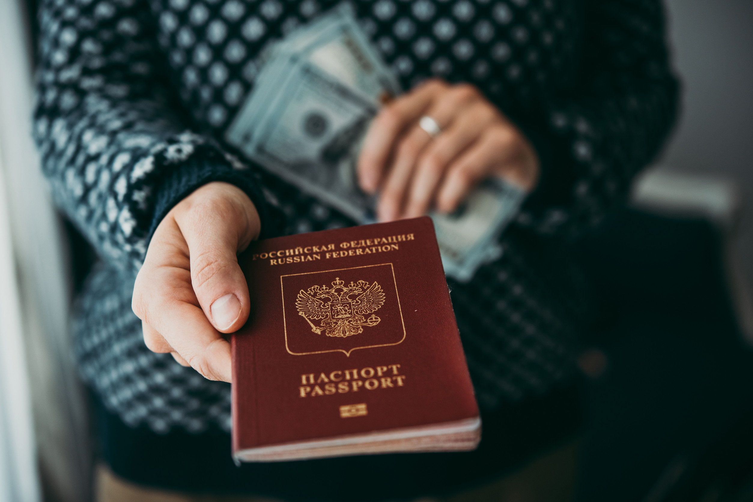 Hands Holding Russian Passport And Us Dollar Bills