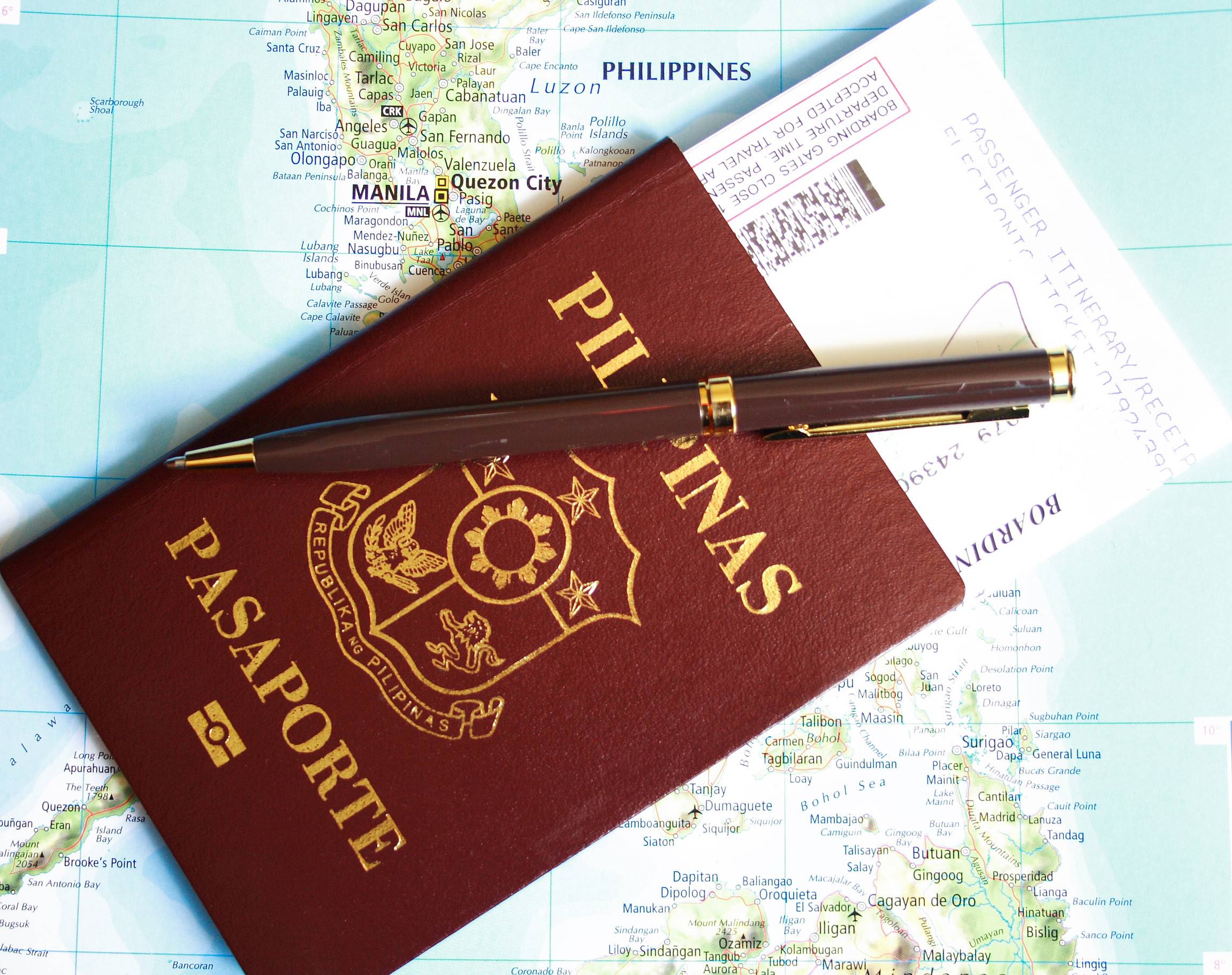 Philippines Passport With Pen And Boarding Pass Over Map Background
