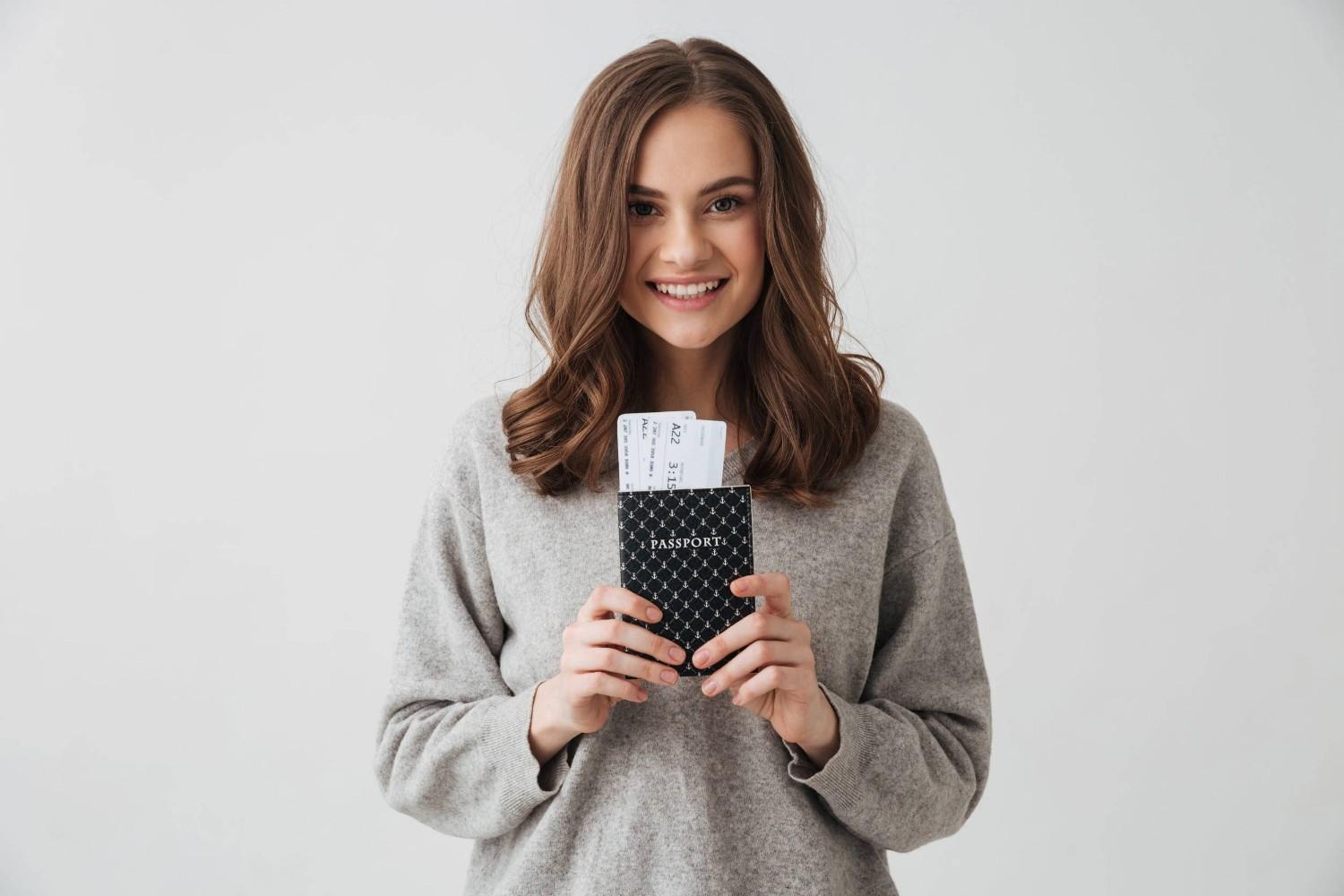 Smiling Brunette Woman in Sweater Preparing to Travel Holding Passport