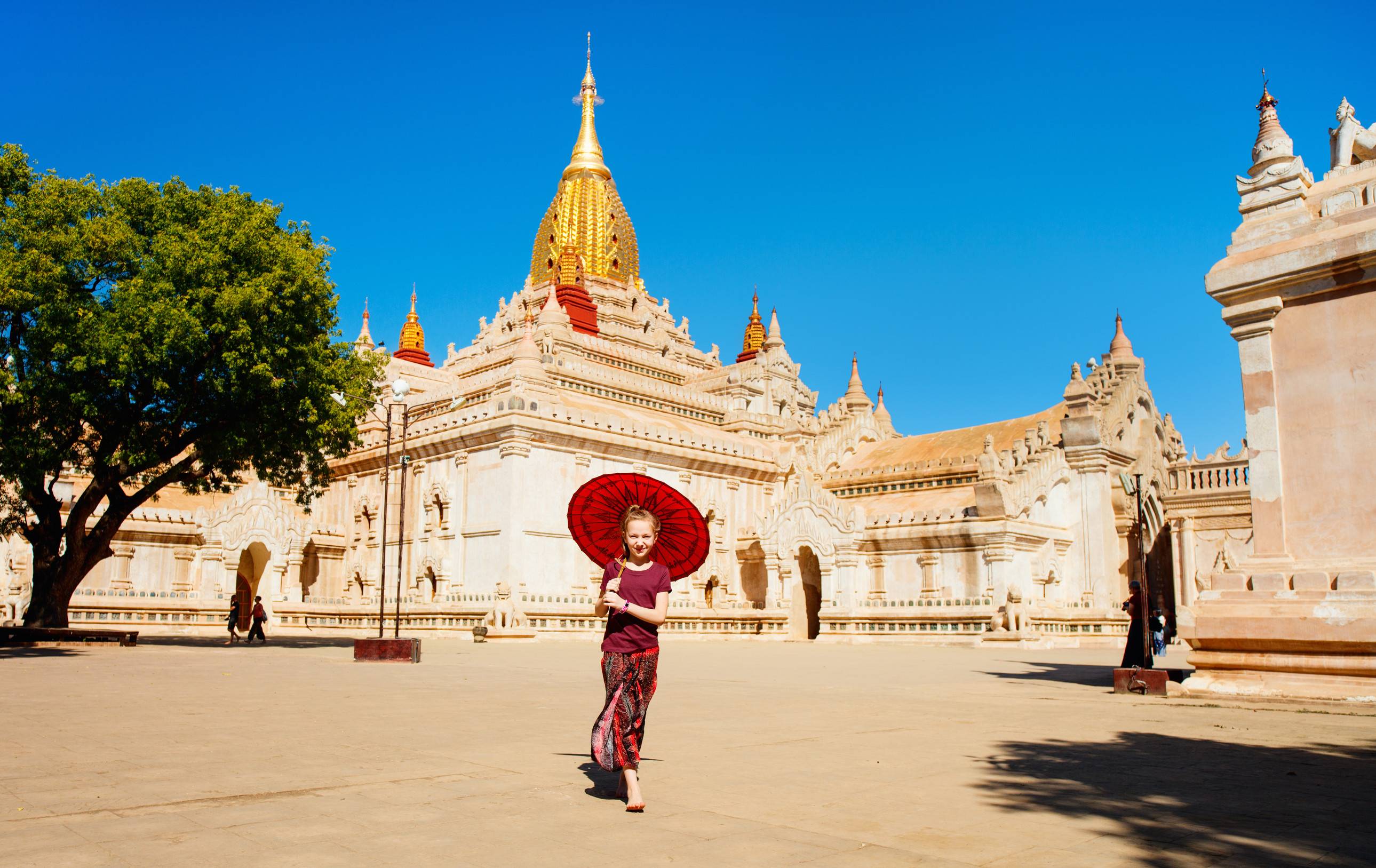 Young girl with traditional Burmese parasol visiting Ananda Pagoda one of Bagan most